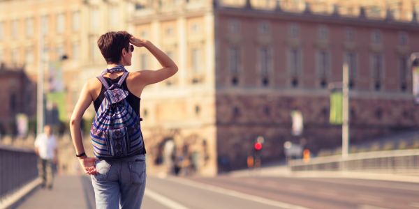 Young person with a backpack looking ahead on a street.