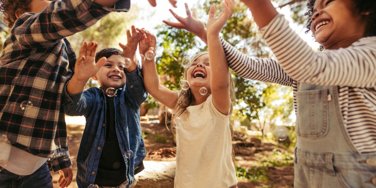 Children joyfully playing with bubbles outdoors.