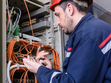 Technician repairing cables in a server room.