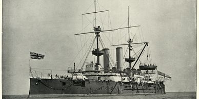 Historical battleship at sea with British flag.