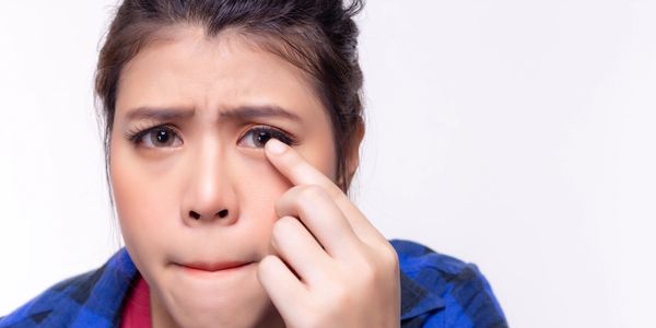 Woman touching her eye with a concerned expression.