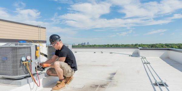 Technician repairing rooftop HVAC unit.
