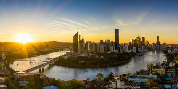 Sunset over a city skyline with a river and bridges.