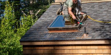 Window cleaner on roof cleaning skylight on a house