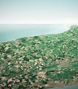 Aerial view of a green coastal landscape with patchwork fields.