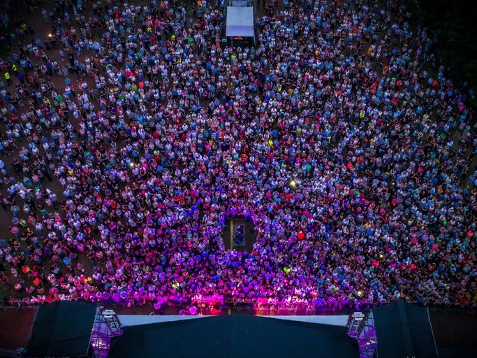 outdoor concert - colorful crowd of people in front of the stage, view from the drone