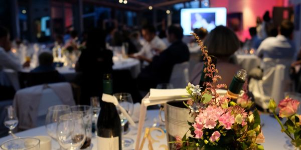 Floral centerpiece at a dinner event with attendees in the background.