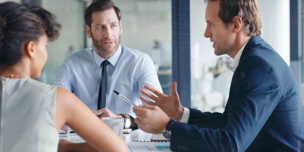 Three colleagues engaged in a serious business discussion in an office.