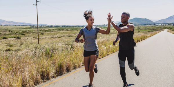 Two people running outdoors giving a high-five.