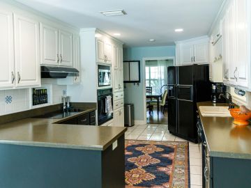 Modern kitchen with white cabinets and black appliances.