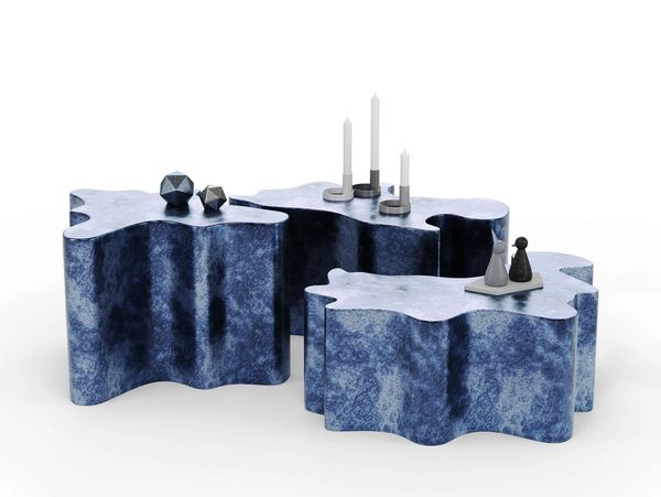 Three irregularly shaped blue marble tables with decorative objects on top.