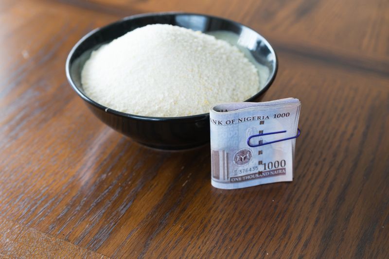 A bowl of Nigerian Garri with Nigerian Naira Notes Spread on table in market
