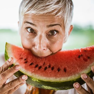 Woman enjoying a large slice of watermelon outdoors.