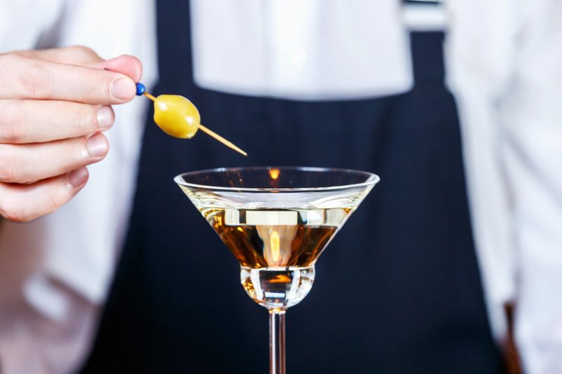 Barman decorating martini cocktail at a nightclub. Nightlife and entertainment concept. Horizontal