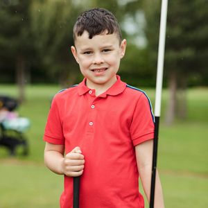 A group of children with golf bags posing outdoors.