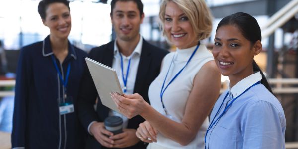 Group of professionals smiling and holding a tablet.
