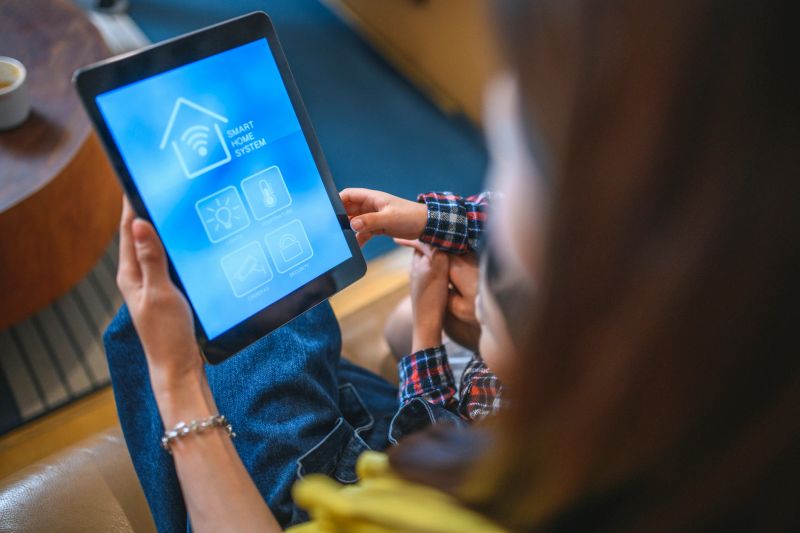 High angle view of a Taiwanese mother showing her young son a smart home system app on a digital tablet.