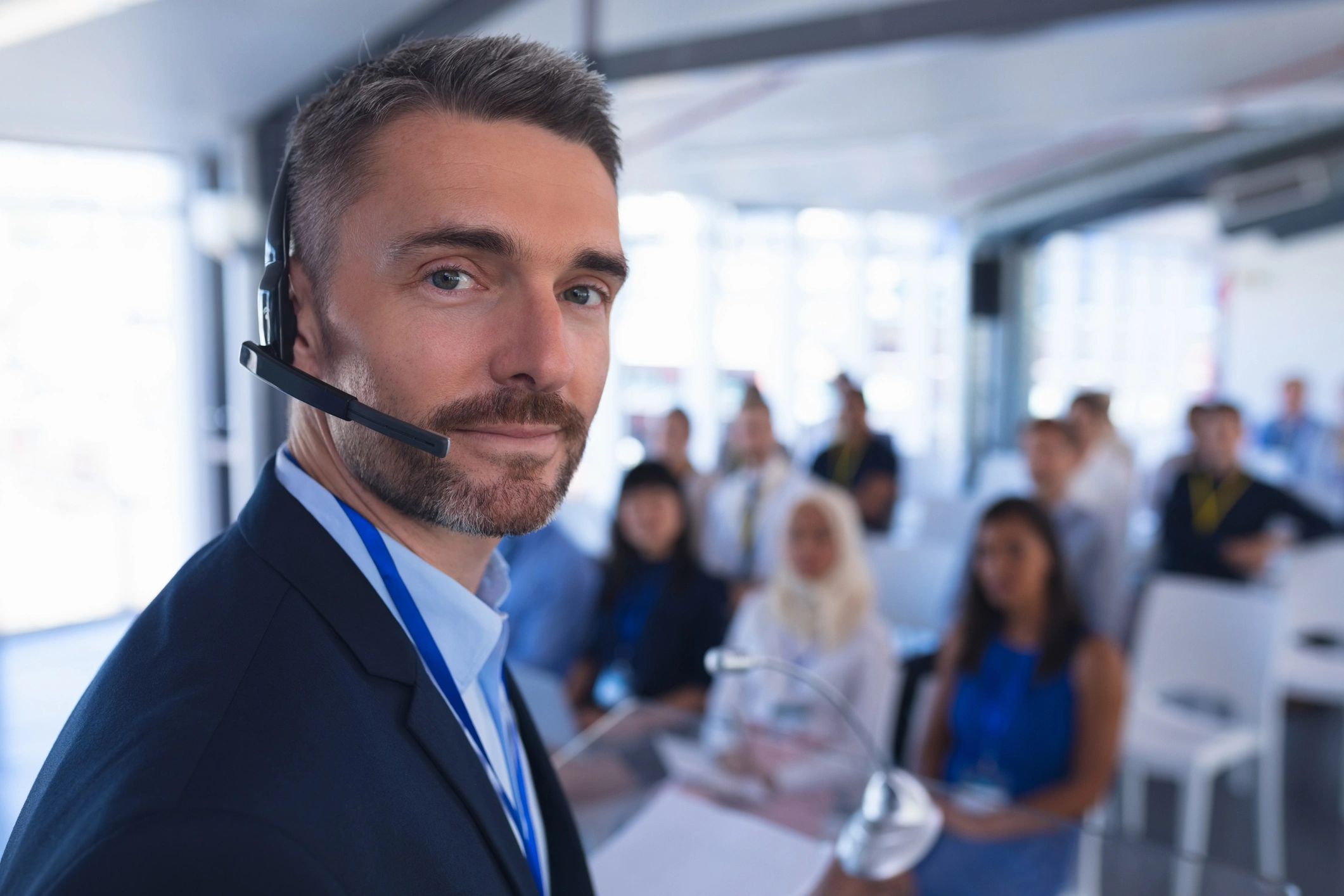 Confident speaker with headset addressing an audience in a modern setting.