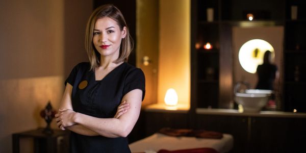 Confident woman standing with arms crossed in a cozy room.