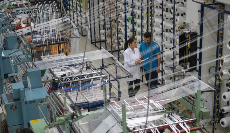 Team of Latin American operators working at a rubber factory supervising a machine - industrial concepts