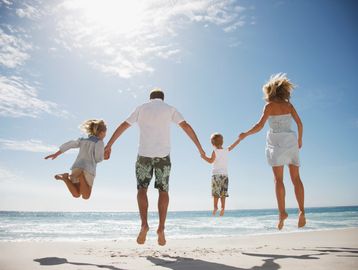 Family jumping joyfully on the beach.