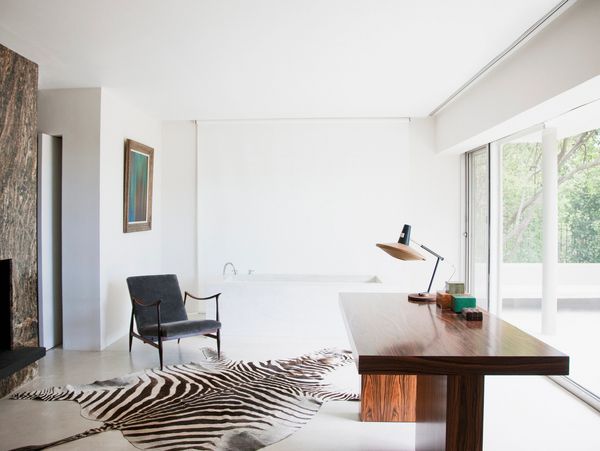 Minimalist room with zebra rug, wooden desk, and large window.