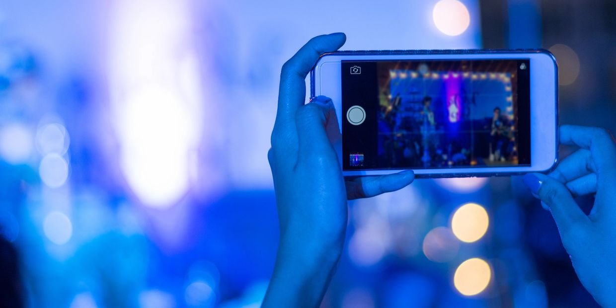 Person capturing a concert on phone at night.