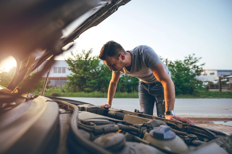 Young handsome caucasian man looking under car hood.