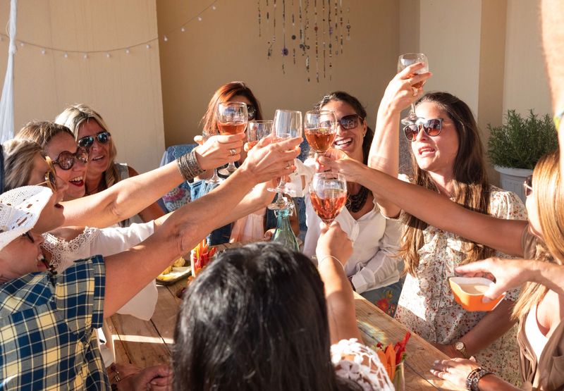 Happy group of people celebrate a birthday. Smiling women with red wineglass. wooden table, food and drink. Friendship concept