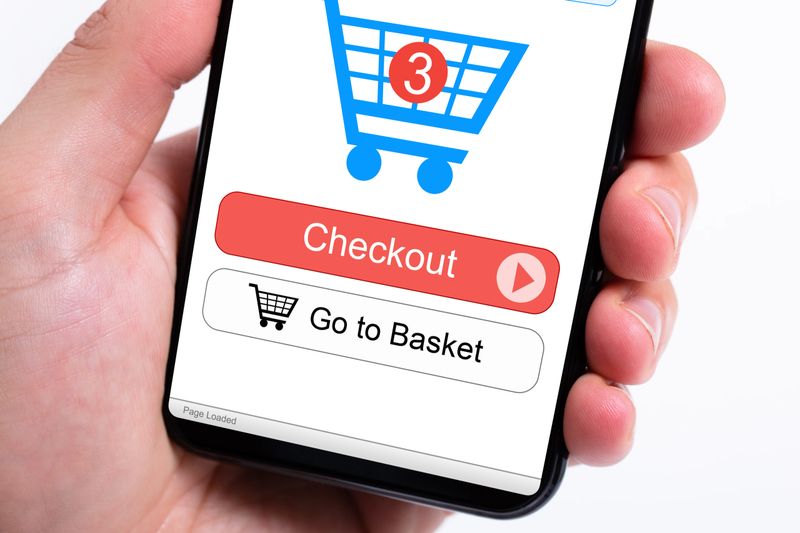 Cropped image of businesswoman's hands using smartphone with online shopping application on screen