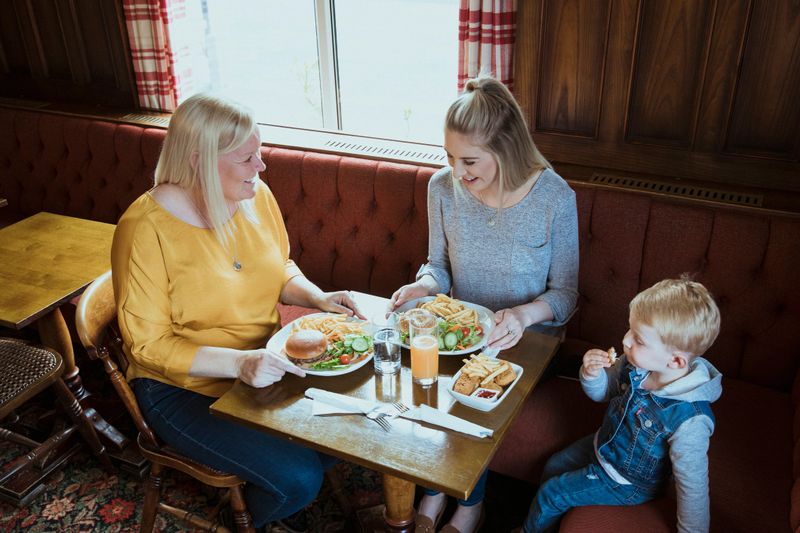 A family enjoy a meal together in their local pub. The image is shot from a high angle view.