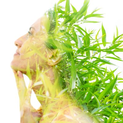 Double exposure of a woman and green bamboo leaves.