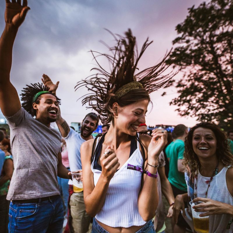 Large group of cheerful friends dancing on an outdoor party.
