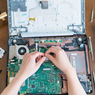Hands repairing a laptop's internal components.