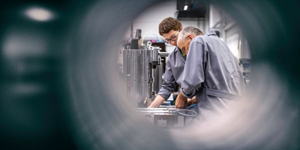 Two engineers working on aluminium extrusions in a factory.