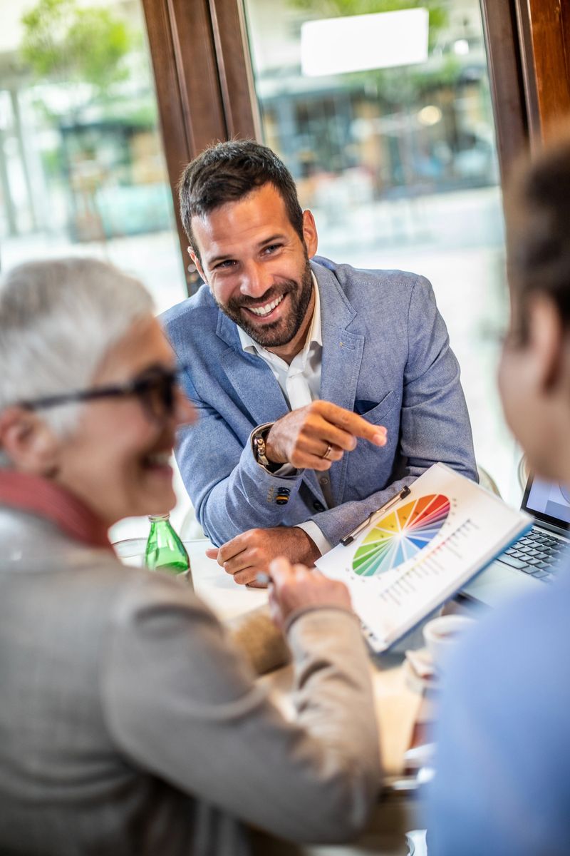 Young successful corporate man presenting an informative pie chart to his female company managers during a business meeting in a cafeteria.