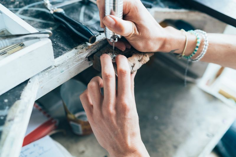 Close up of hands of Female Jeweler crafting silver jewelry in workshop