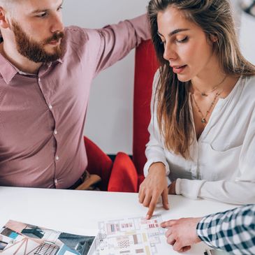 Three people discussing interior design plans around a table.