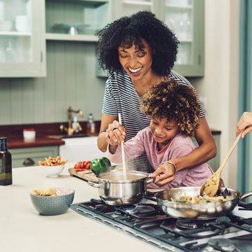 A mother and child cooking together happily in the kitchen.