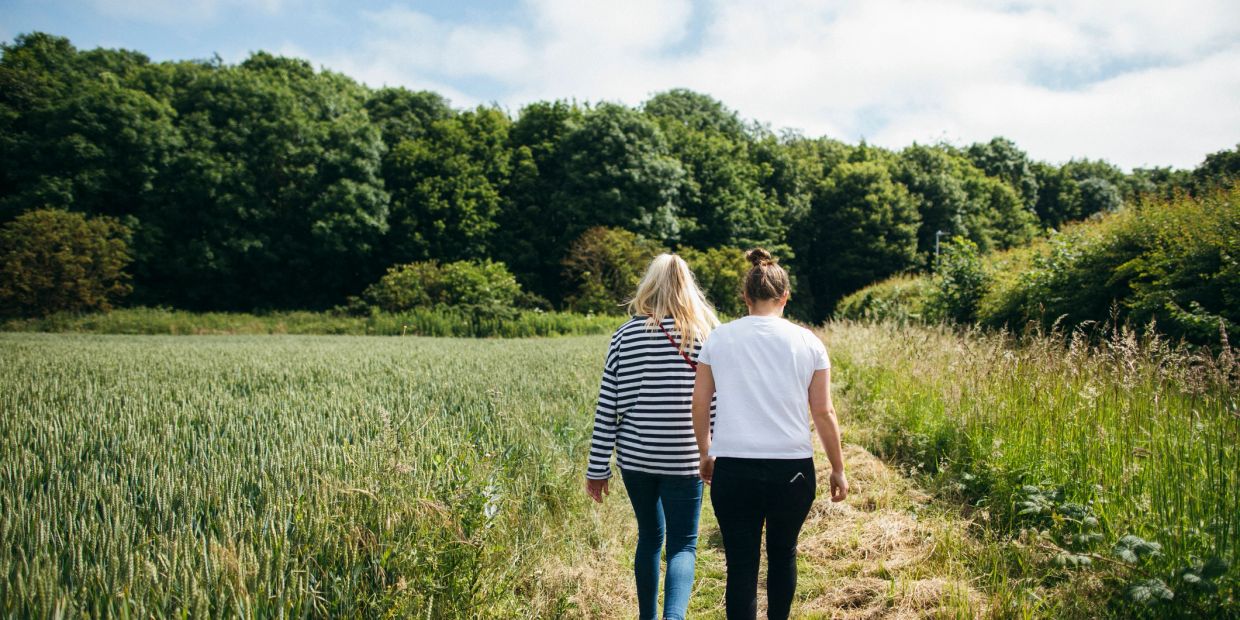 Twee vrouwen wandelen langs een pad in de natuur.
