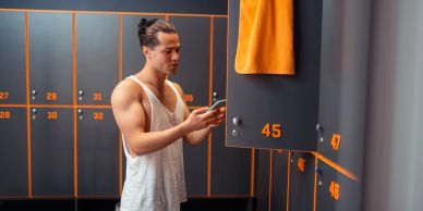 Man opening a locker in a gym changing room.