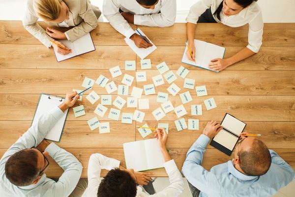 Team brainstorming session with notes scattered on a wooden table.