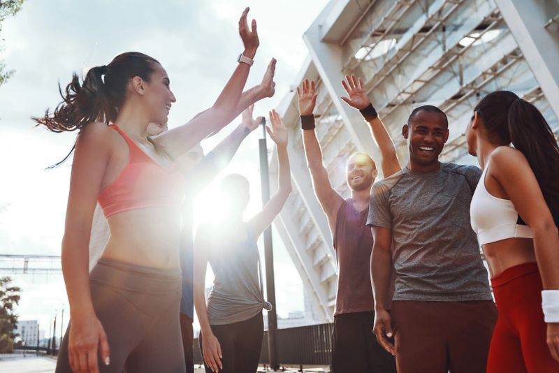 Treino em grupo ao ar livre, pessoas se exercitando e se motivando mutuamente.