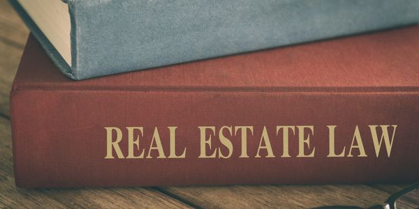 A thick book titled Real Estate Law on a wooden surface.