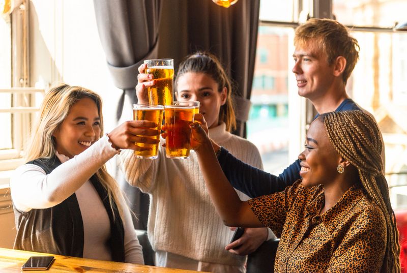 A group of four friends sharing celebratory drinks in a British pub.