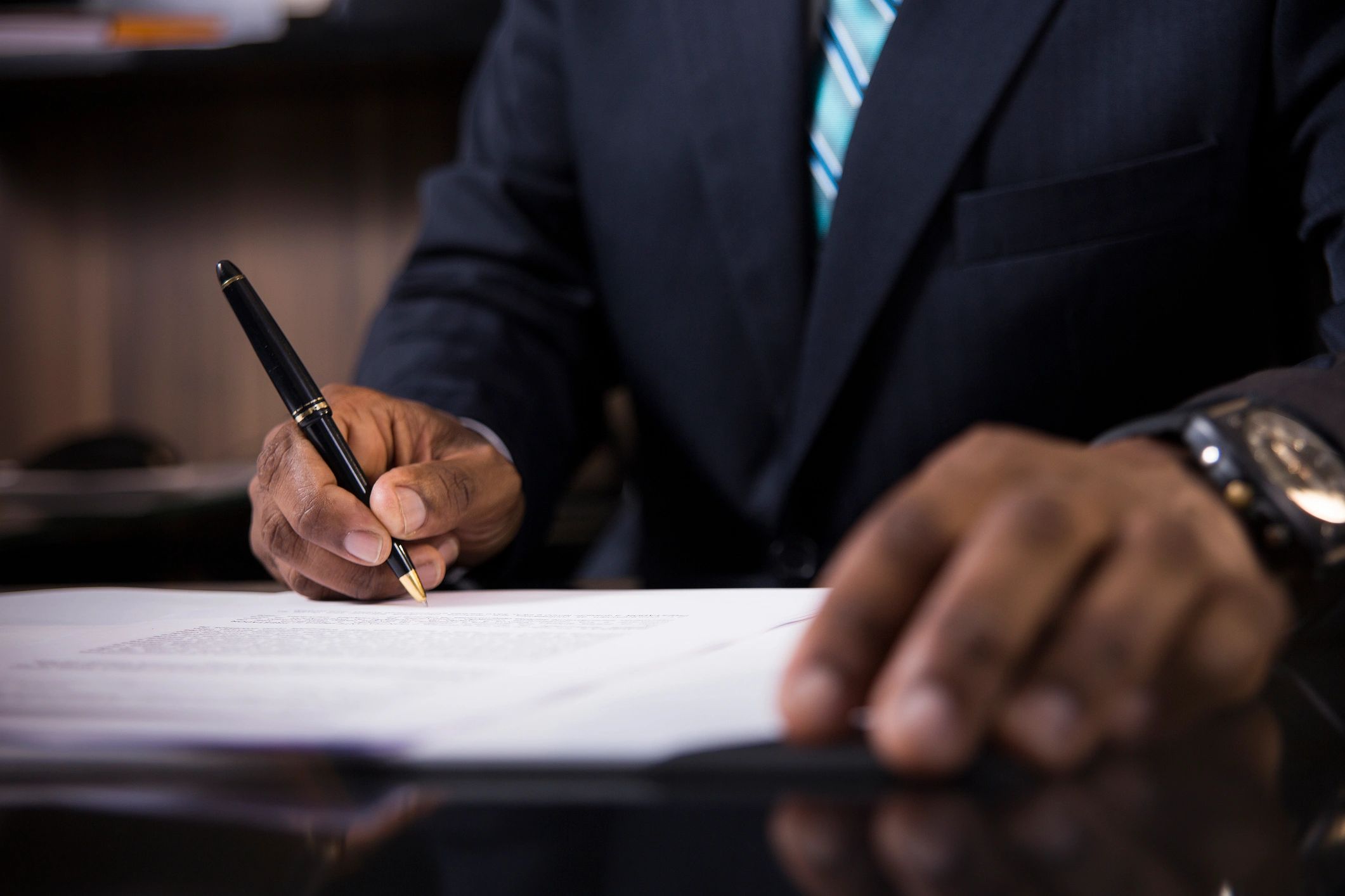 close-up of a professional signing legal documents with a pen.