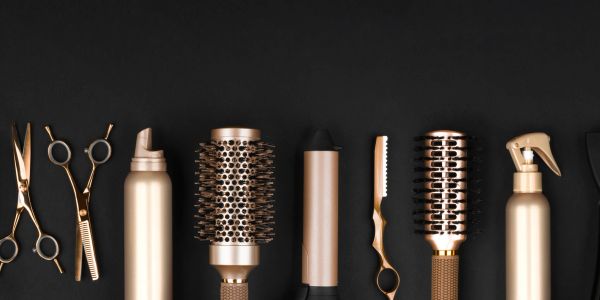 Gold-colored hair styling tools arranged in a row on black.