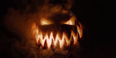 Glowing sinister jack-o'-lantern with sharp teeth and smoky background.