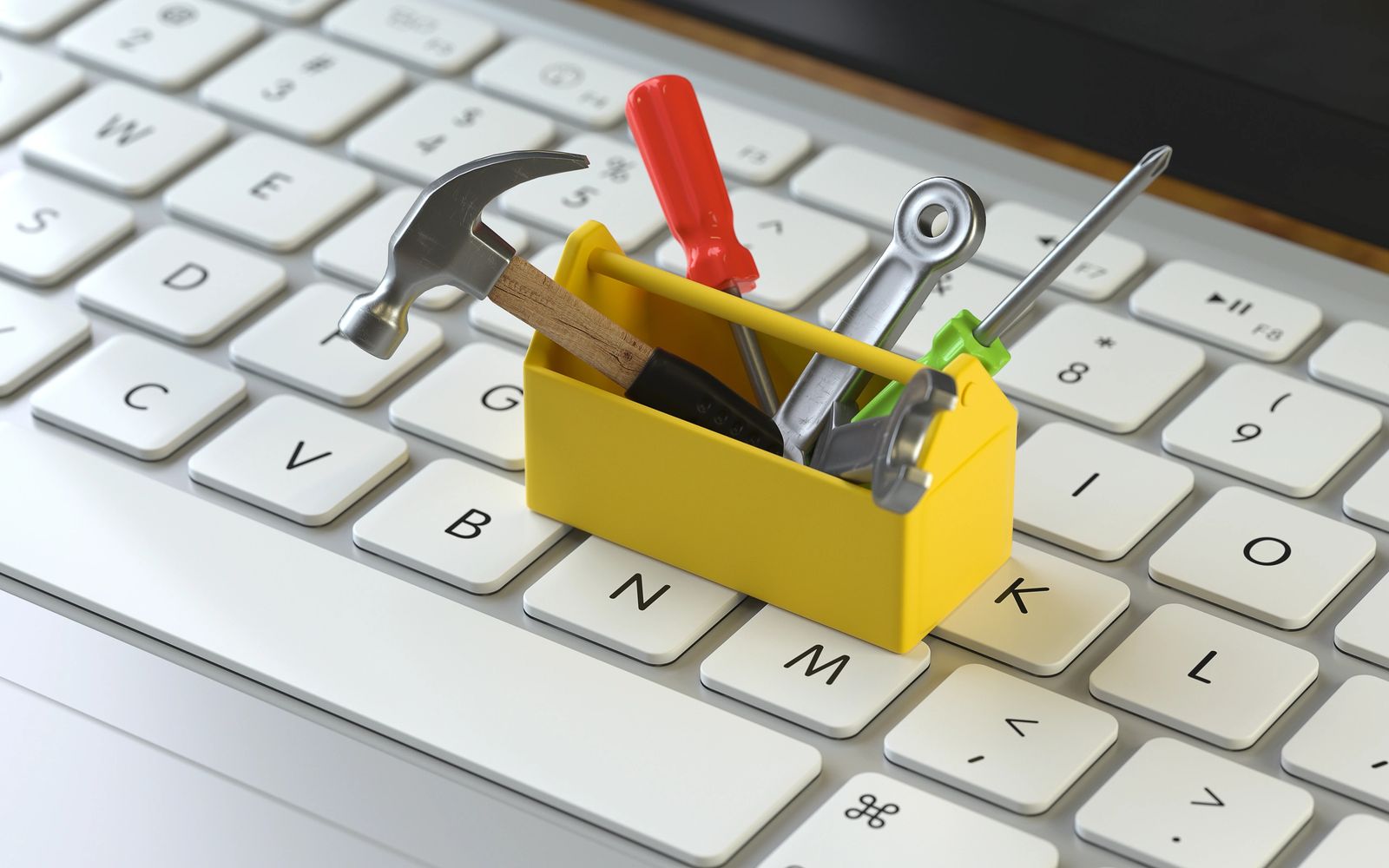 Miniature toolbox with tools on a computer keyboard.