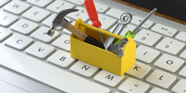Miniature toolbox with tools on a computer keyboard.